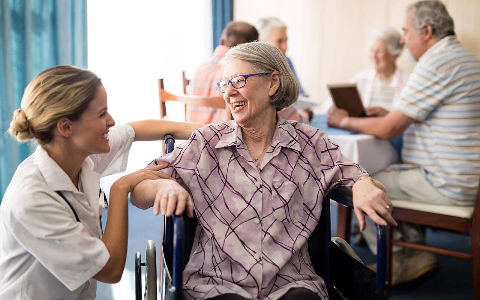 A young nurse talking with elder woman sitting in a wheelchair | Outlook Wealth Advisors