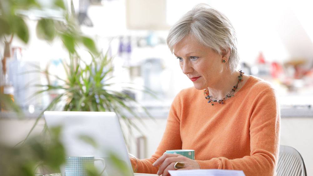 An elderly woman in an orange sweater is looking for the best retirement tax planning advisor to help her with her retirement financial planning | Outlook Wealth Advisor