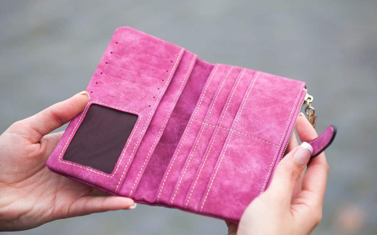 A woman holding an empty wallet in her hands thinking about strategies for improving her retirement budget | Outlook Wealth Advisors