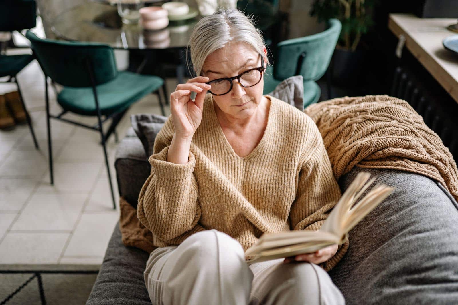 Senior woman lying on a sofa and reading about retirement income planning strategies | Outlook Wealth Advisors